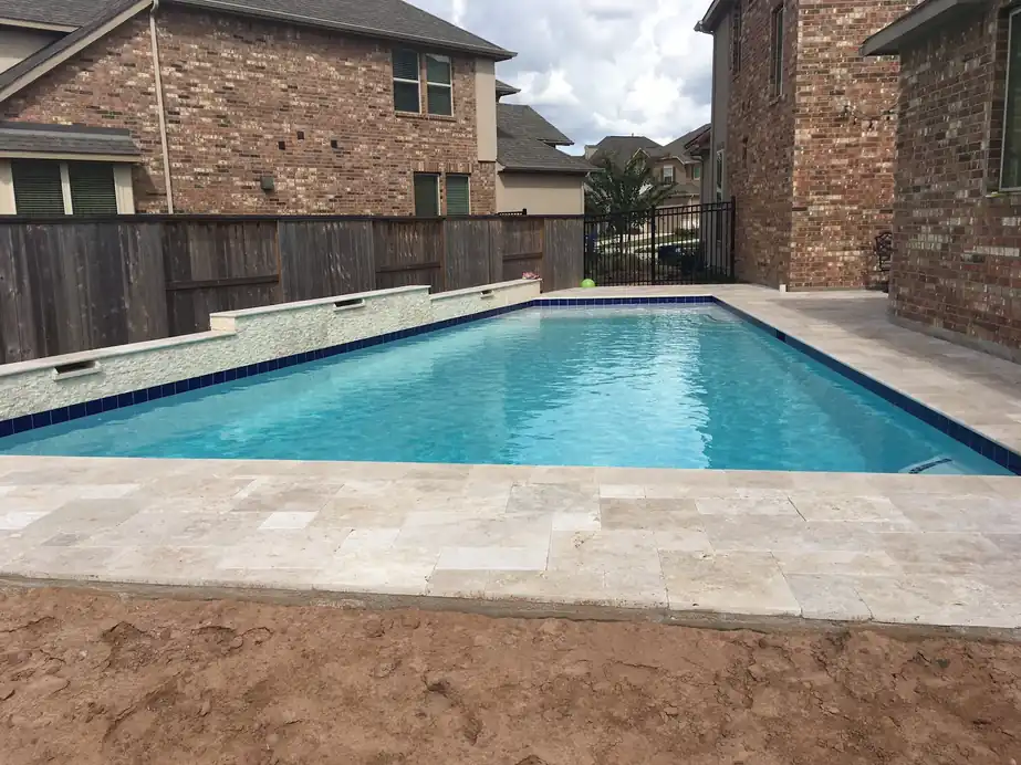 New pool with travertine coping, ready for the yard to be finished around it