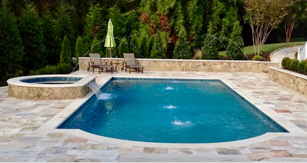 Travertine-coped pool with laminar jets, a raised spa and a stone waterfall wall